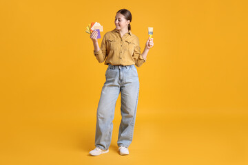 Woman with paintbrush and color samples on orange background