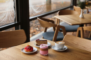 Aromatic coffee and delicious desserts served on wooden table in cafe