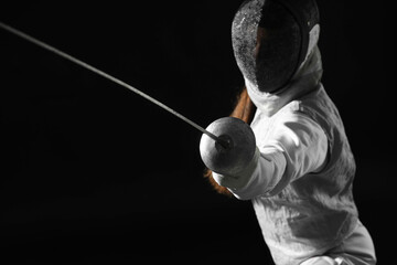 Fencer with epee practicing on black background, selective focus