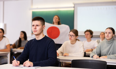 High school teacher tells students about Japan and holds a Japanese flag in her hands.