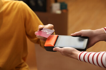 Man paying with credit card via terminal in cafe, closeup