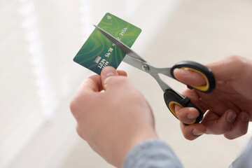 Man cutting his credit card indoors, closeup