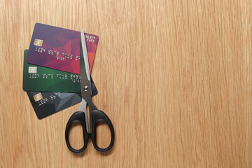 Credit cards and scissors on wooden table, top view. Space for text