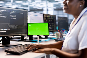Programmer using green screen tablet to check for signs of failure in data center supercomputers....