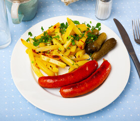 Grilled sausages served with french fries and pickled cucumbers