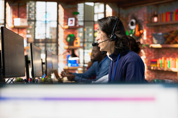 Call center senior agent uses artificial intelligence to enhance customer interaction and resolve inquiries efficiently. Experienced Asian customer service employee using AI communication technologies