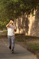 Young hispanic boy jogging and hydrating outdoors for a healthy lifestyle
