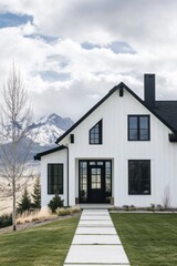 Fototapeta premium A contemporary white home featuring bold black accents stands out against breathtaking mountain views, all set in a picturesque landscape bathed in daylight