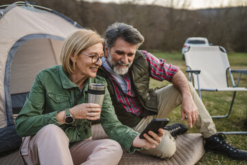 mature couple husband and wife enjoy on camping trip and use cellphone