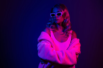 Stylish young woman with blond hair and pink light in a dark purple background