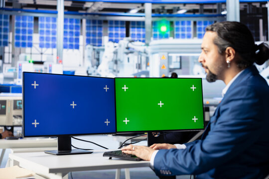 Engineer in photovoltaics factory reviewing system logs on isolated screen computer displays to identify errors. Photovoltaic plant worker adjusting manufacturing parameters on mockup PC monitors