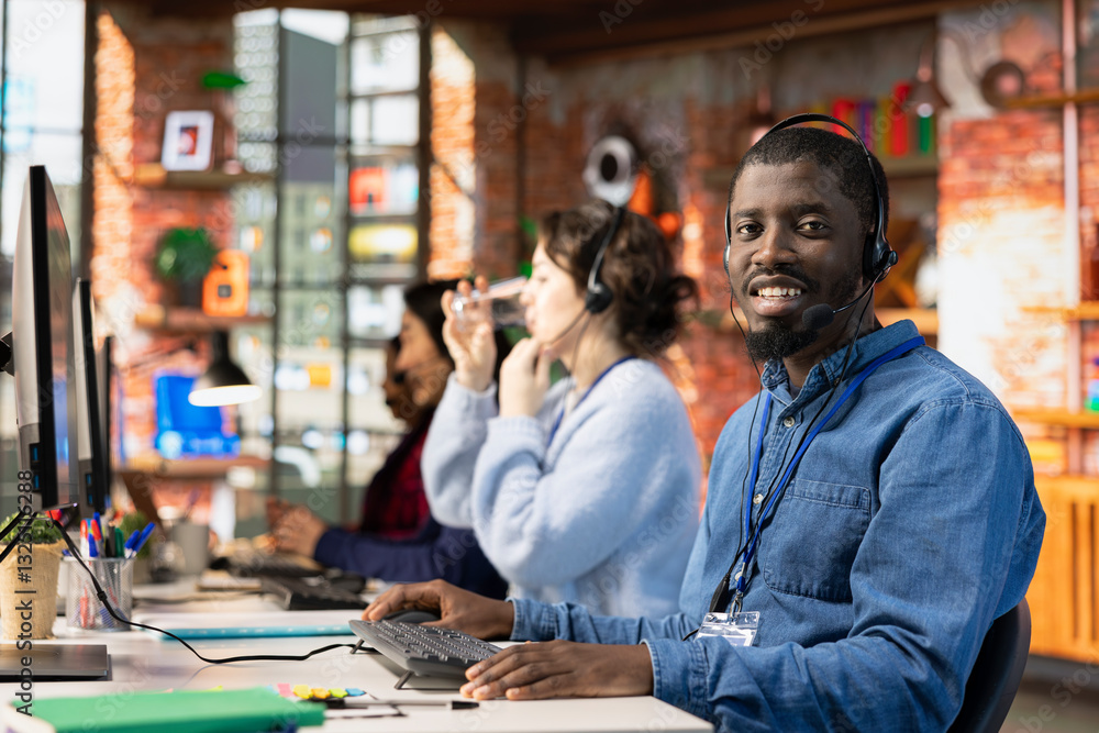 Poster portrait of smiling call center worker typing on pc keyboard, assisting customers through digital co