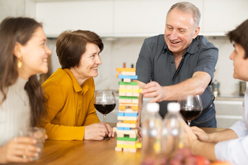 Emotional family, parents with children excitedly playing Jenga game at home