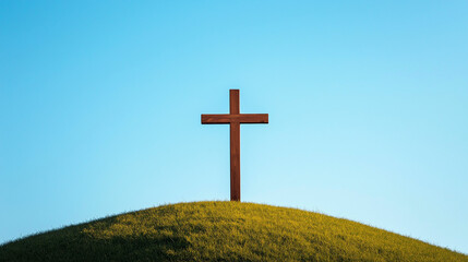 Holzkreuz steht einsam auf sanfter H&uuml;gelwiese unter blauem Himmel

