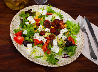 Delicious salad with vegetables, mozzarella and roasted sliced sausages