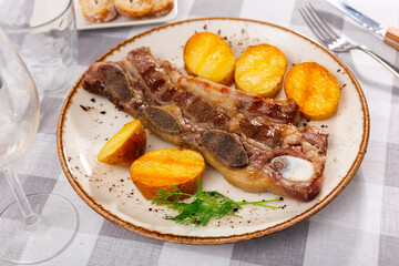 Service plate containing grilled steak and slices of potato with necessary table laying