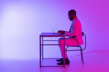 Stylish Man Working on Laptop in Vibrant Purple Lighting