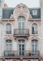 Obraz premium Architectural close-up of curved windows and sculpted floral details on a historic European townhouse. Romantic Art Nouveau elegance in urban design.