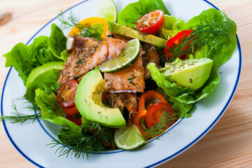 Appetizing fish salad with tender roasted trout fillet, avocado, cherry tomatoes and greens