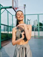 Young woman enjoying exercise outdoors with a bright smile against a basketball court backdrop