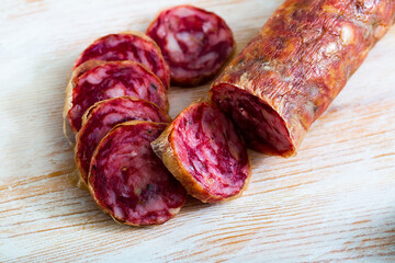 Popular Spanish summer sausage Salchichon from chopped pork on wooden surface