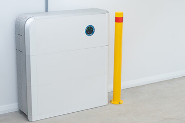 Large white battery for solar energy storage installed in a garage with safety post
