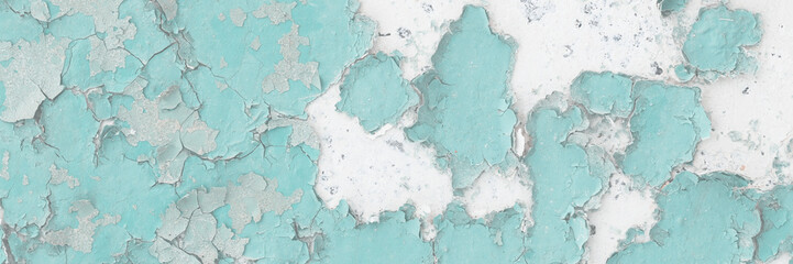 Green peeling paint on the wall. Old concrete wall with cracked flaking paint. Weathered rough painted surface with patterns of cracks and peeling. High resolution texture for background and design.