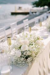 Bouquet of flowers next to glasses and bronze goblets on a set table in the garden