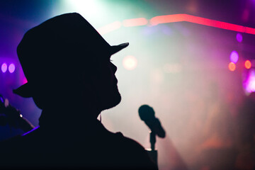 silhouette of a man with a hat singing at night