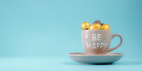 Coffee cup with chocolate eggs on a blue background.