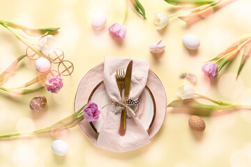 Table setting with Easter eggs and beautiful tulips on yellow background