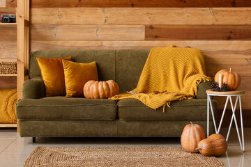 Interior of cozy living room with green sofa and pumpkins