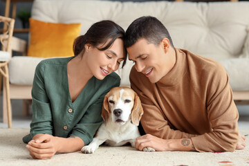 Young couple with cute Beagle dog at home