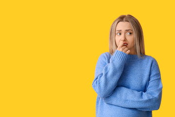 Young woman feeling awkward on yellow background