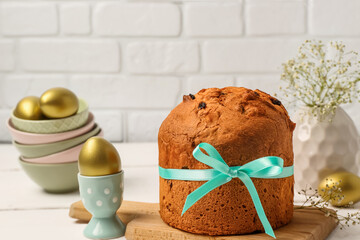 Wooden board with delicious Easter cake and painted eggs on white wooden table