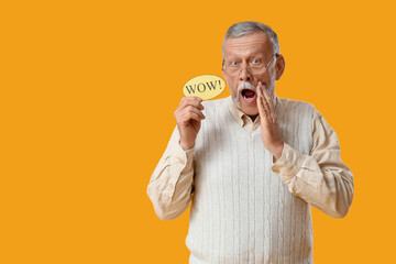 Shocked senior man holding speech bubble with word WOW on yellow background