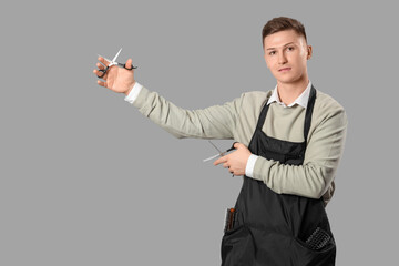 Male barber with scissors on grey background