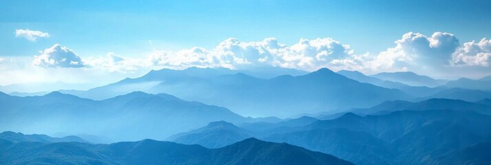 Fototapeta premium Majestic Blue Mountain Range Under Bright Clouds with Soft Mist and Scenic Horizons for Nature and Landscape Photography