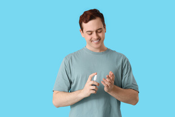 Young man with sanitizer on blue background