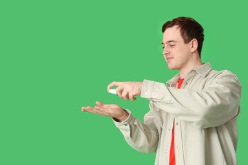 Young man with sanitizer on green background