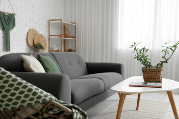 Light interior of modern living room with bamboo stems on coffee table, armchair and sofa