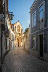 Street view in the historic center of Santarém in Portugal, with the beautiful facade of the church of Nossa Senhora da Graça in the background, illuminated by the sun.