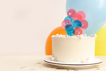 Cake with balloons for birthday party on table against white wall