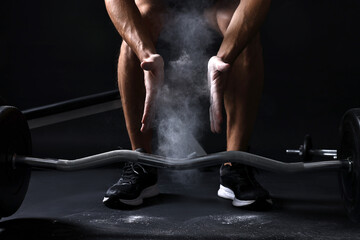 Man clapping hands with talcum powder before training with barbell in gym, closeup