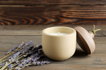 Soy wax candle, lid and lavender flowers on wooden table, space for text