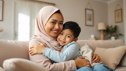 Asian Muslim mom embraces and son sitting on couch in living room