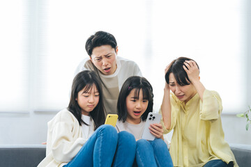 スマホを見ながら困った表情の小学生の女の子の家族
