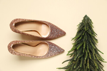 Shiny high heeled shoes and decorative Christmas tree on beige background, flat lay