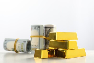 Shiny gold bars and money on light background, selective focus