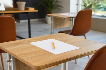 School desks with sheet of paper and pencil prepared for exam. Closeup